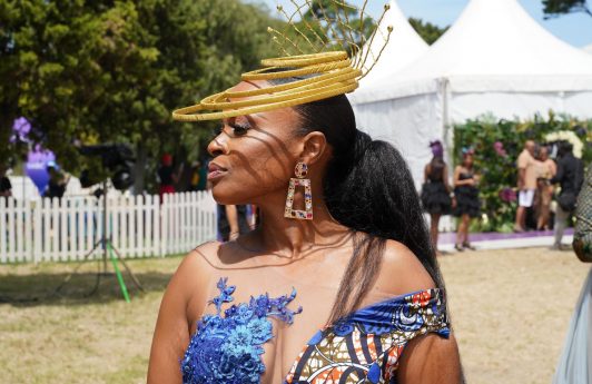 woman at the sun met 2020 with a slicked back low ponytail and big, gold halo accessory