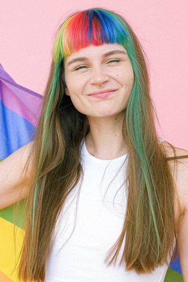 Pride: woman with rainbow fringe and long brown hair holding a pride flag
