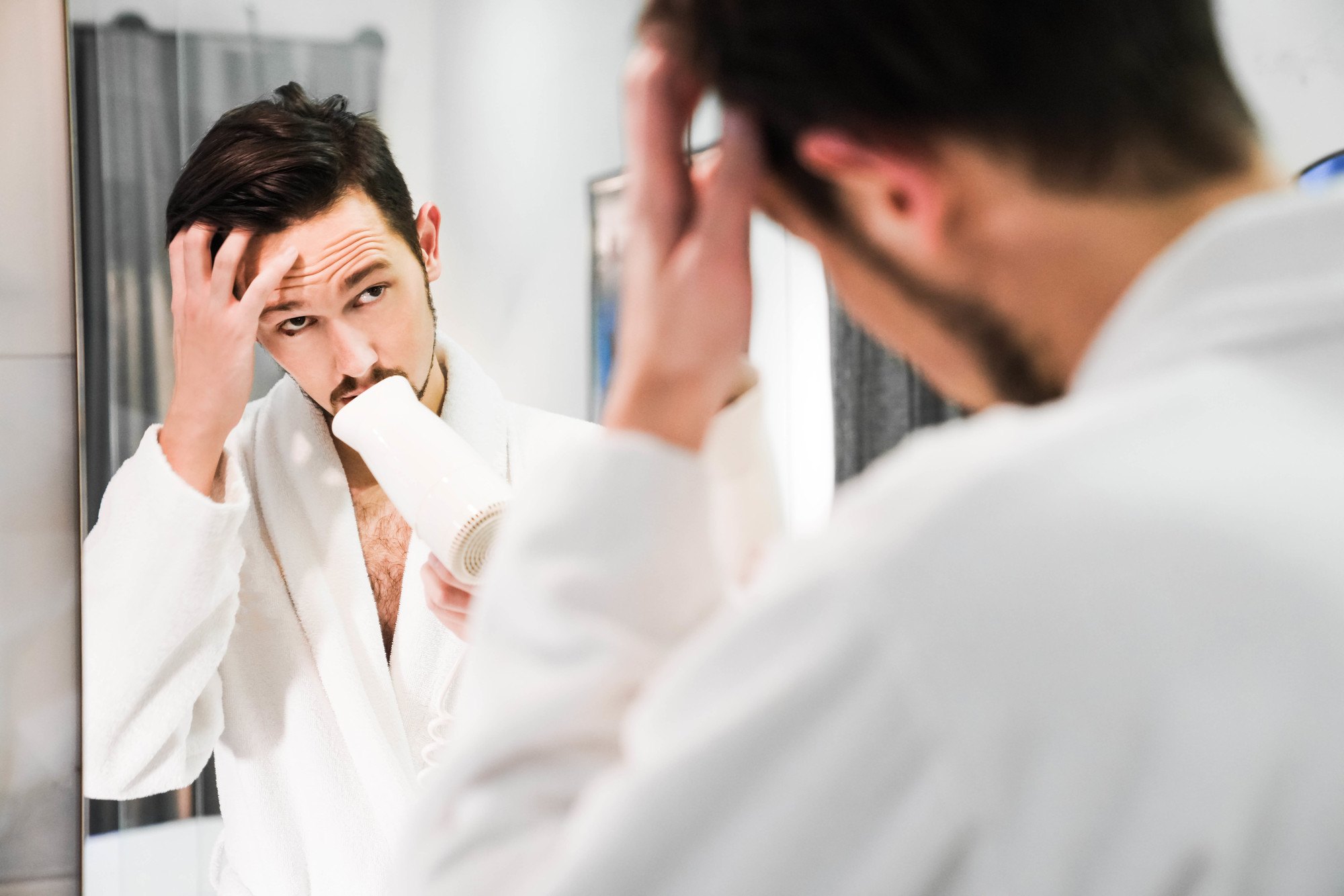tips for men: man drying his hair with a blowdryer