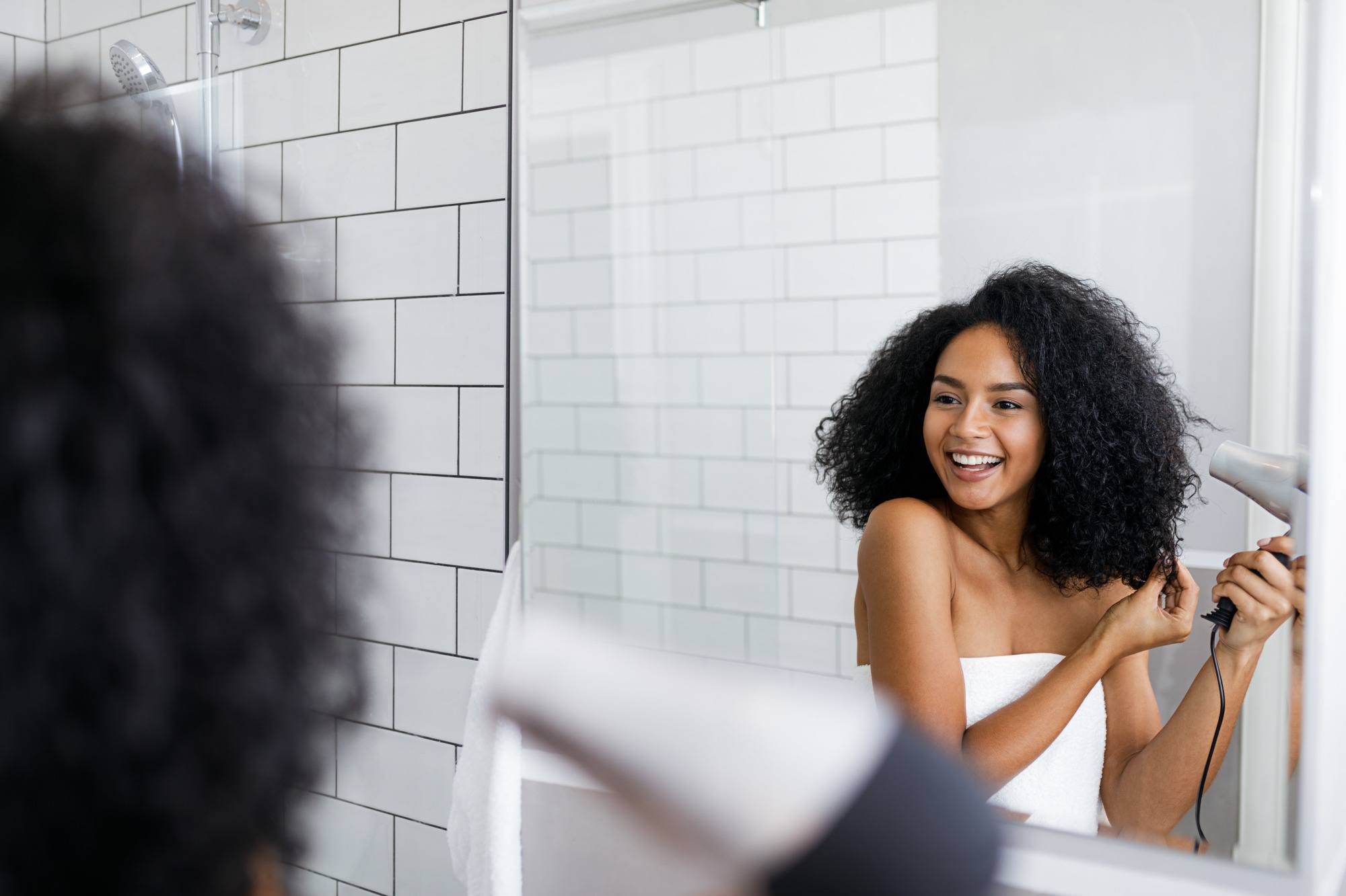 woman with curly hair using a hair dryer