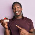 Man with braided hair holding a slice of cake