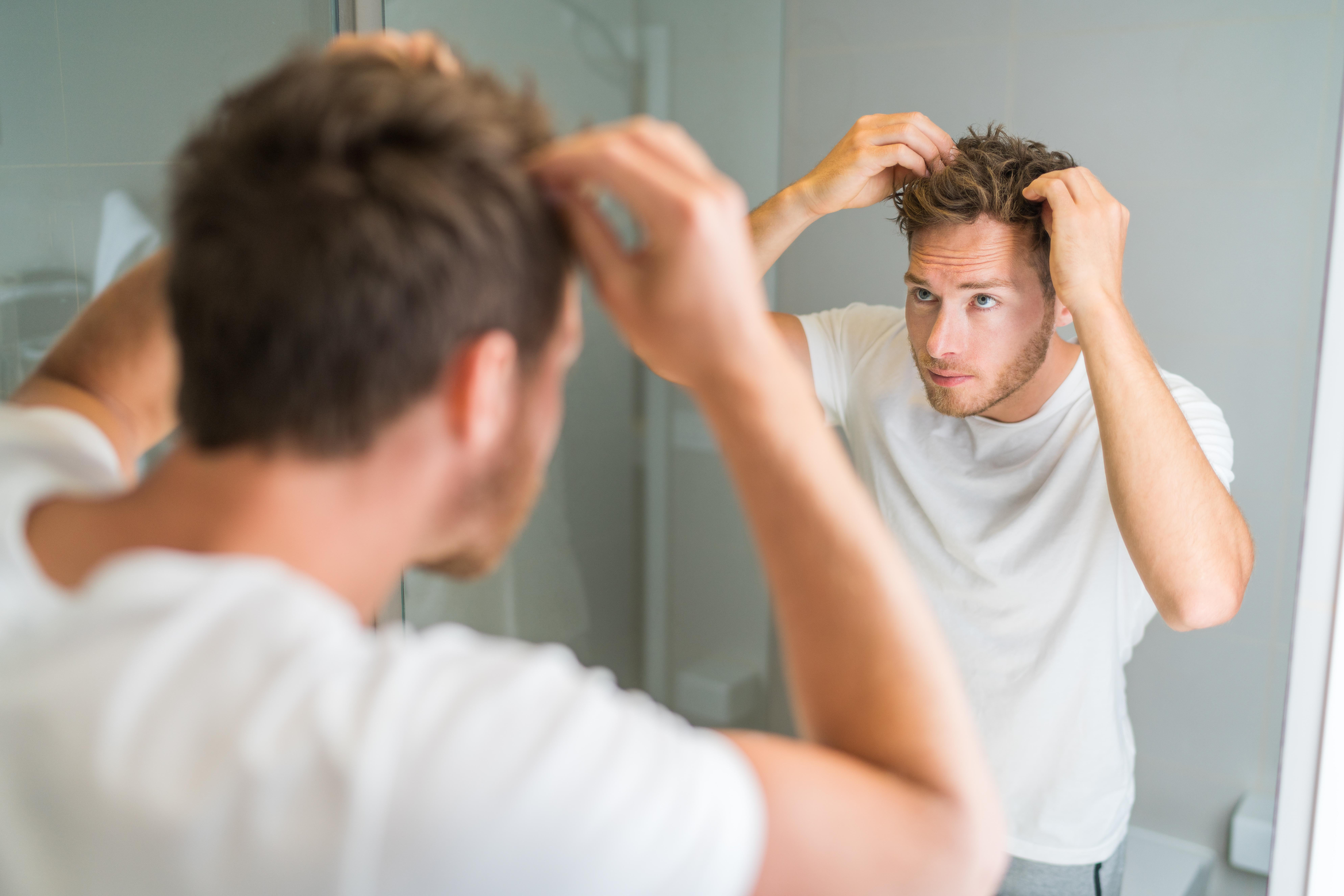 streamlined haircare routine: man looking in a mirror and styling his hair