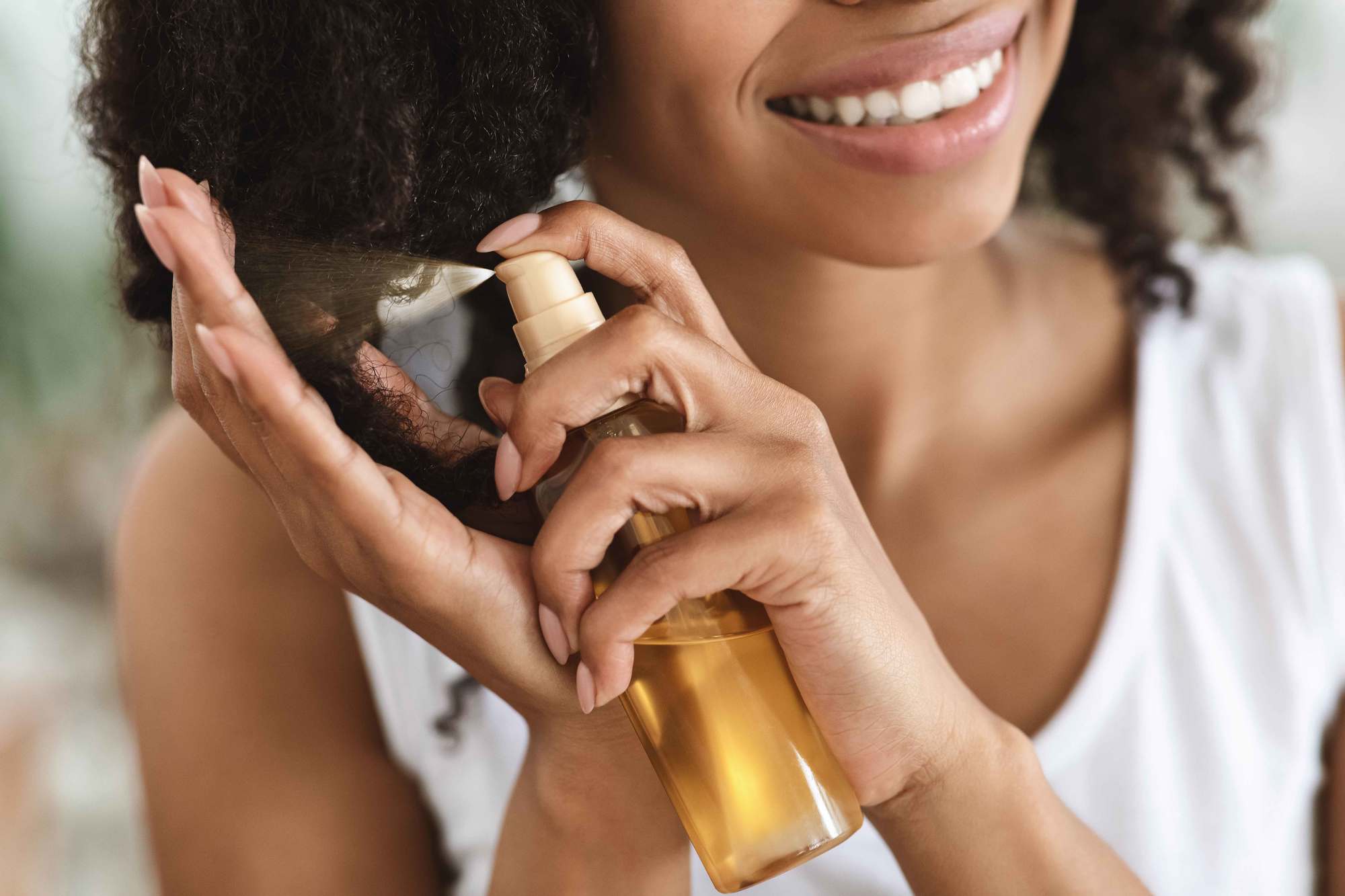 best-smelling hair products: woman spraying a hair product onto her hair