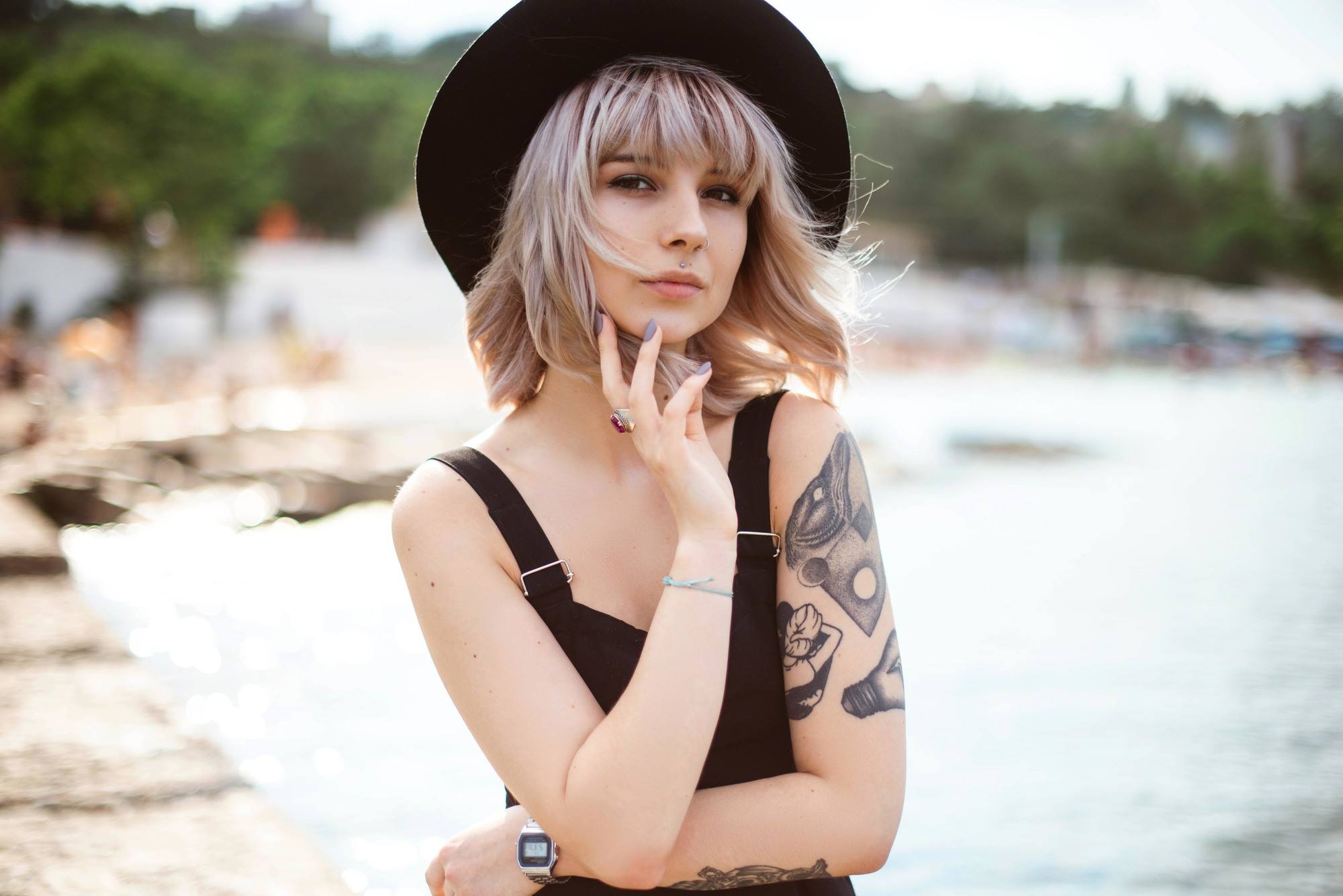 blonde bob hairstyle: woman with a messy bob hairstyle with a fringe; wearing a black hat