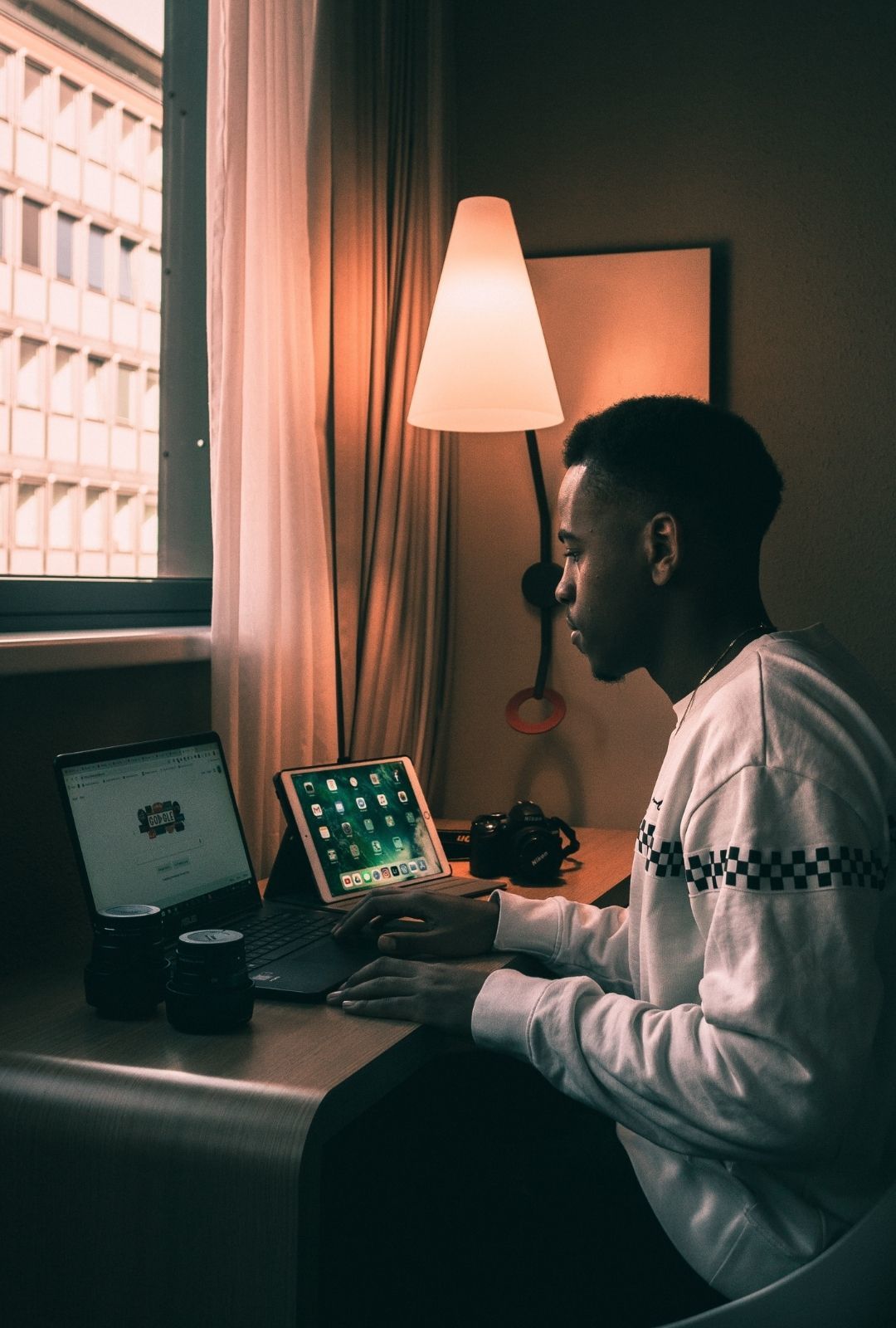 man sitting down at a table, with a laptop and iPad