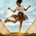 workout hairstyle: image of a woman dancing, with natural hair tied into a high puff hairstyle