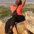 woman sitting at the edge of a mountain with her hair tied in braids