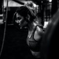 workout hairstyle: woman lifting weights with her hair tied in a messy topknot