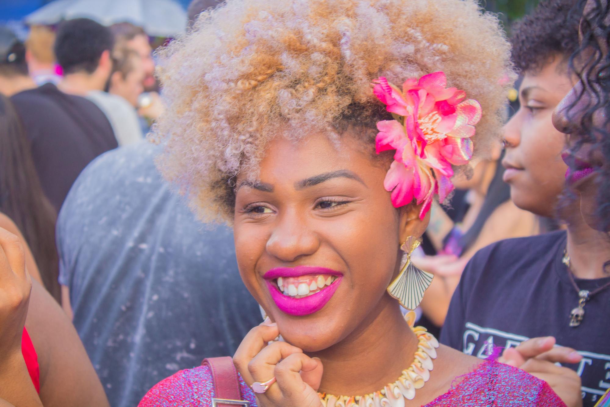 woman with blonde afro hair and a pink flower accessory
