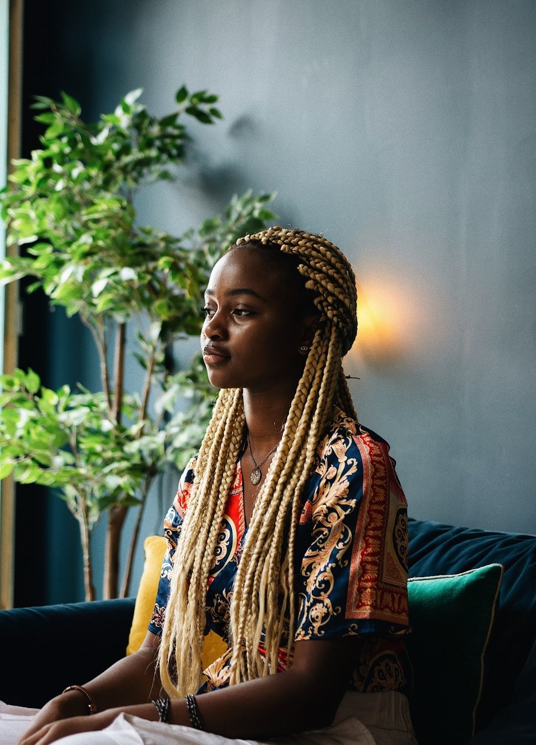 woman with long blonde braids tied into a loose half-up ponytail