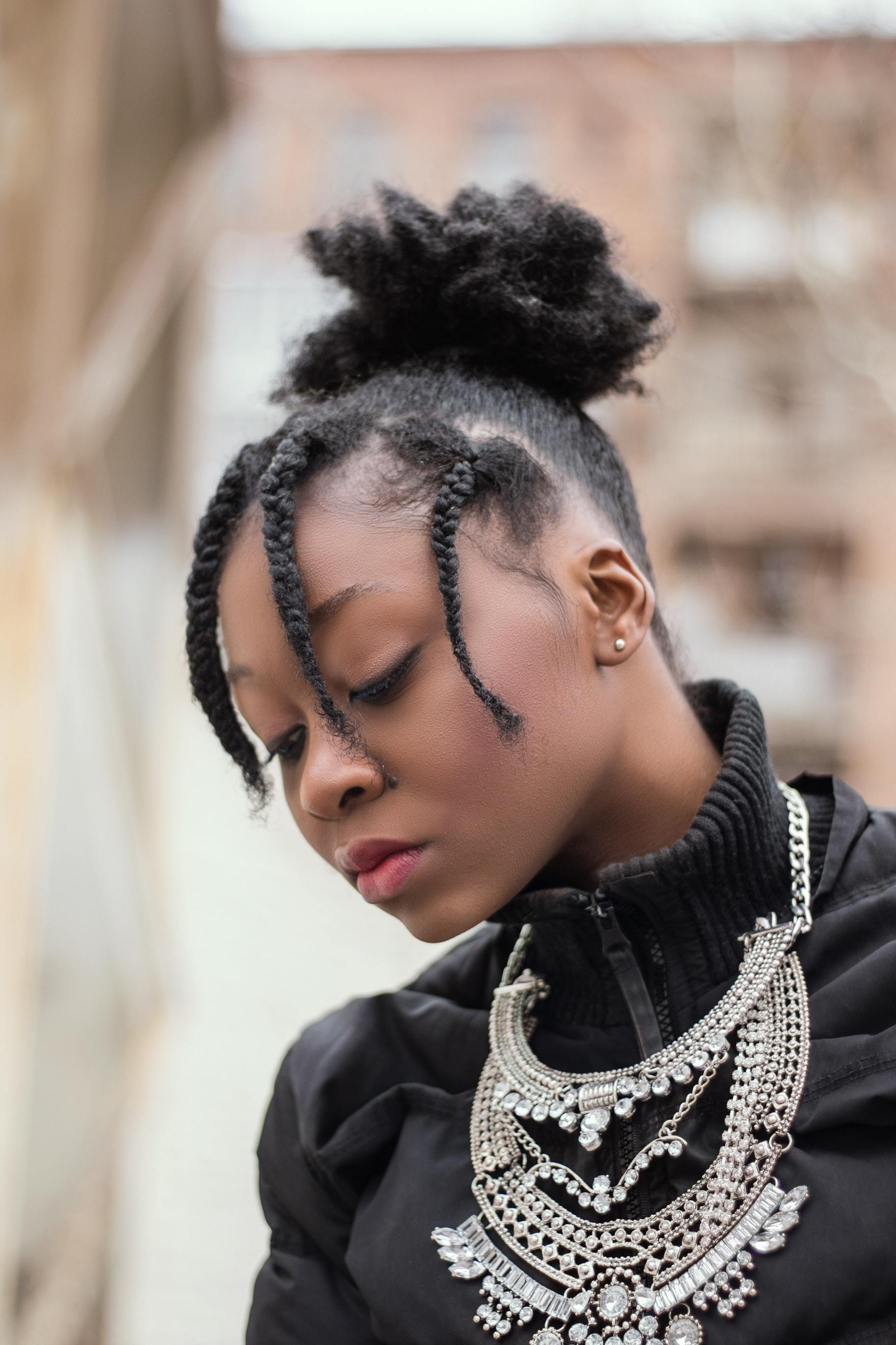 half braided hairstyles: woman with her hair tied into a neat high puff with her fringe styled into three braids