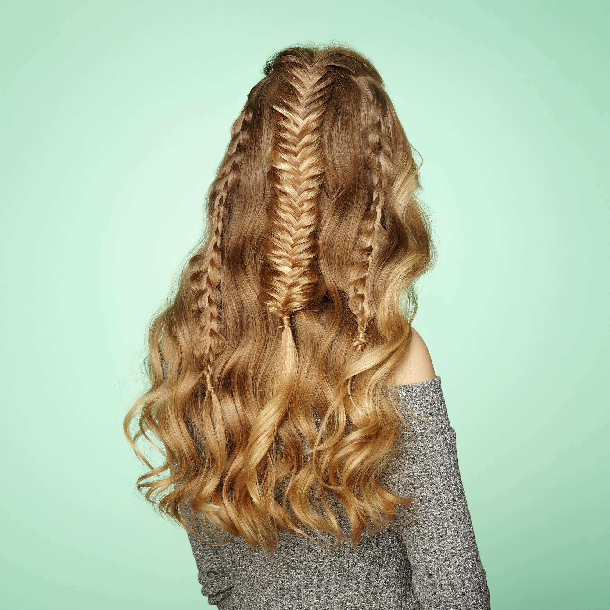 woman with long wavy blonde hair plaited into one half-up fishtail plait and two smaller regular plaits