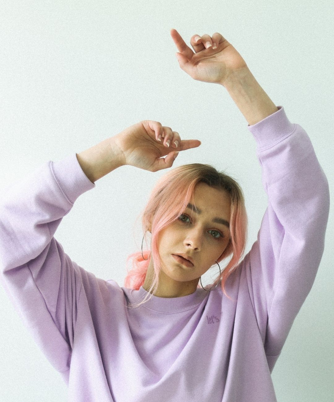 woman with pastel pink hair tied into a low ponytail