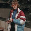 Stranger Things hairstyles: woman with a chin-length, medium-brown hair, thick side-fringe and a half-up ponytail tied with a scrunchie