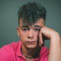 Stranger Things hairstyles: man with curly hair styled into a pompadour hairstyle, with short, faded sides