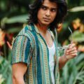 man with thick, shoulder-length straight hair that has a deep side path and loads of volume