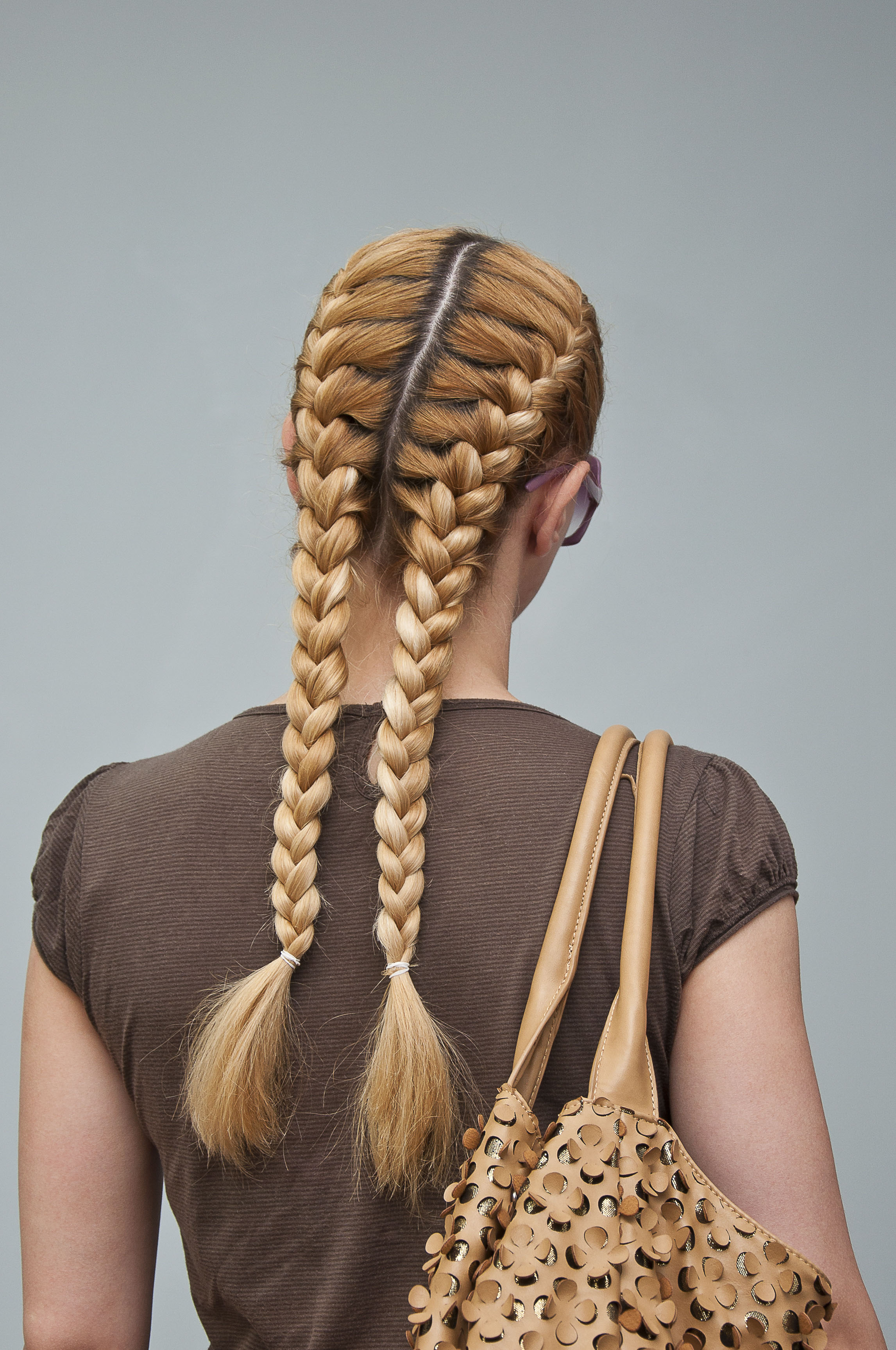 woman with medium-length, light-brown dark-blonde ombre hair, plaited into two french braids
