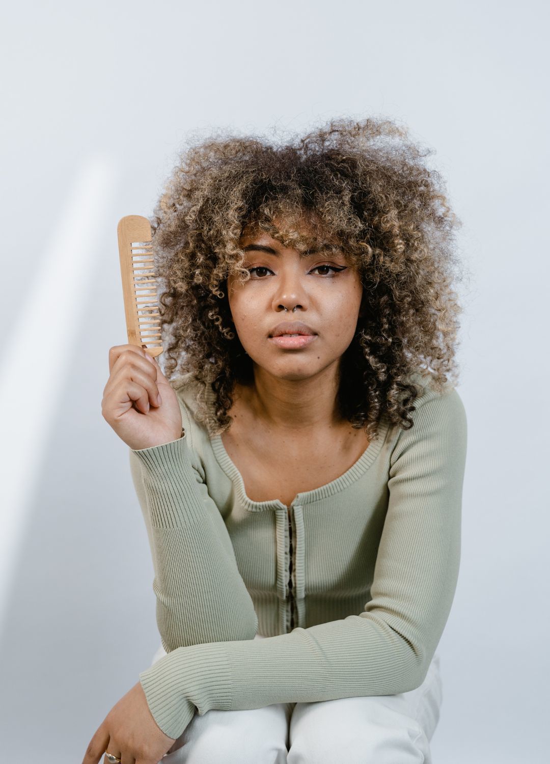 woman with naturally curly hair with blone highlights and a fringe