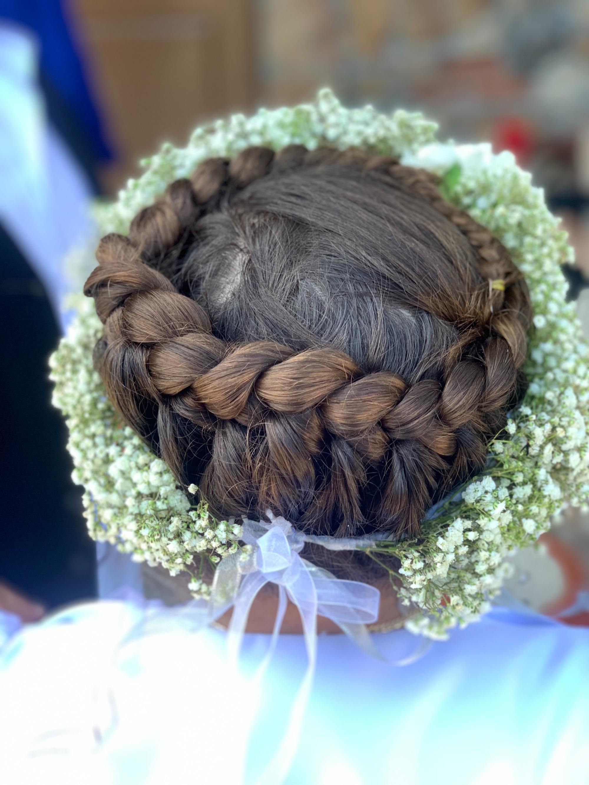 braids around your head: woman with dark brown hair, tied in a thick braid that is wrapped around her head and worn with a flower crown placed around the braid