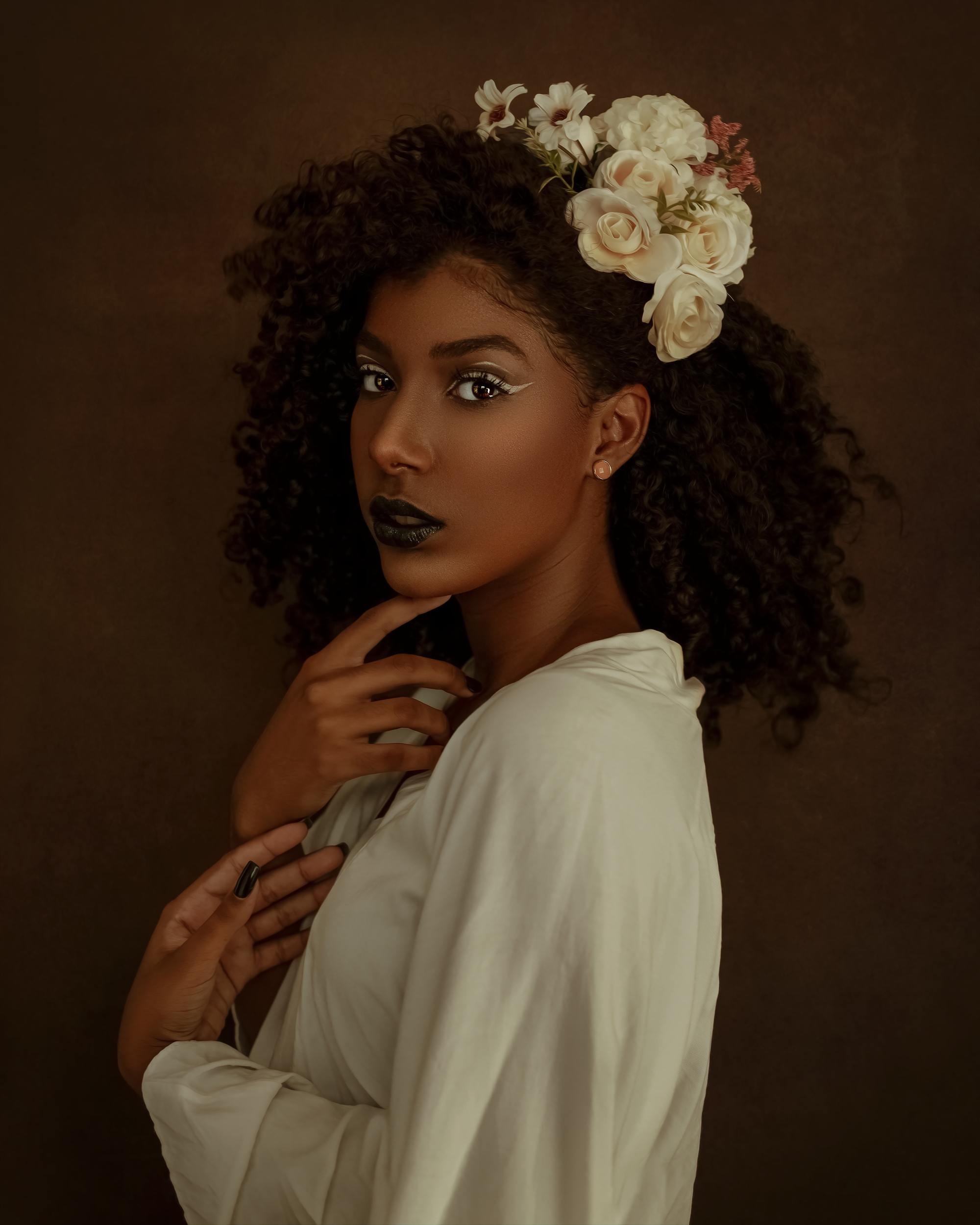 woman with naturally curly hair, with one half pinned up and decorated with big white flower accessories