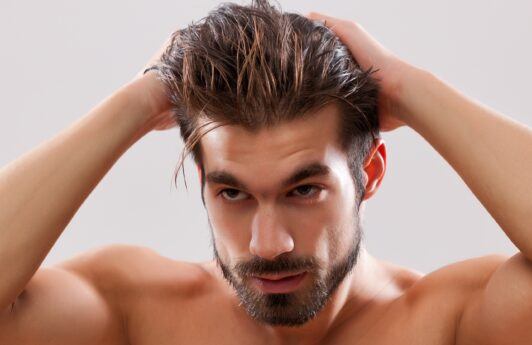 Hombre con barba poniéndose gel para el cabello