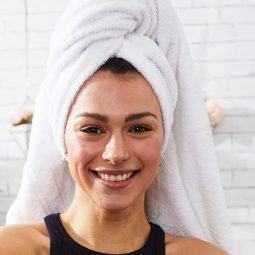 Mujer sonriente con toalla en la cabeza
