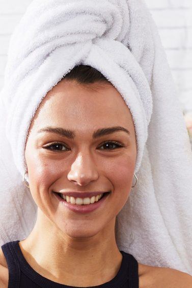 Mujer sonriente con toalla en la cabeza