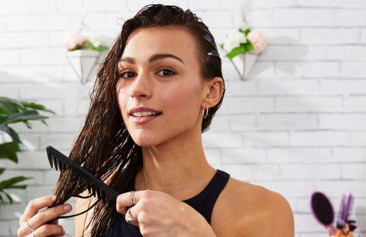 Mujer demostrando cómo desenredar el cabello con un peine de púas separadas