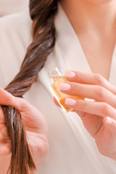 Mujer aplicándose aceite de keratina en el cabello largo