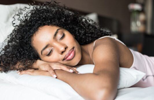 Mujer con cabello rizado dormida en una cama
