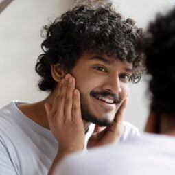 Hombre cuidándose la barba frente al espejo