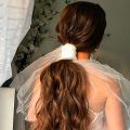 Peinado de coleta baja para novia con velo corto moderno