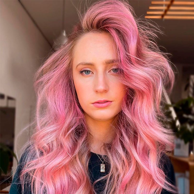Mujer con cabello rosa fuerte ondulado con volumen