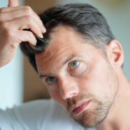 Hombre con cabello canoso probando una prótesis capilar