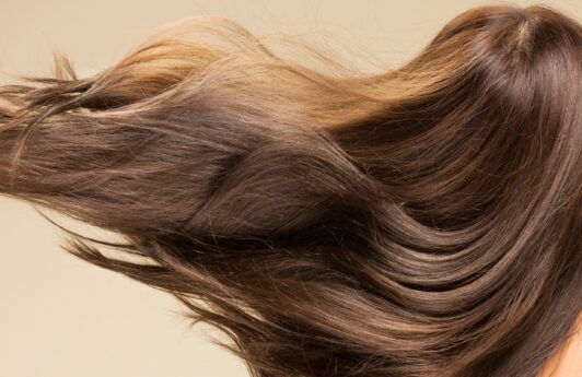 Mujer con cabello largo y lacio volándose con el viento