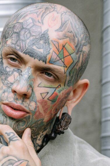 Hombre calvo con tatuaje en la cabeza y la cara