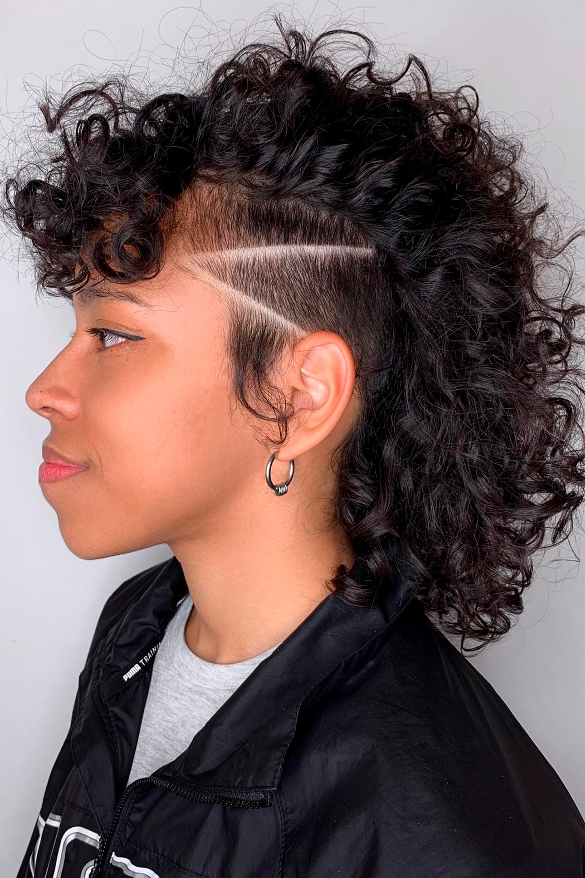 Mujer con corte undercut lateral y grecas en cabello chino