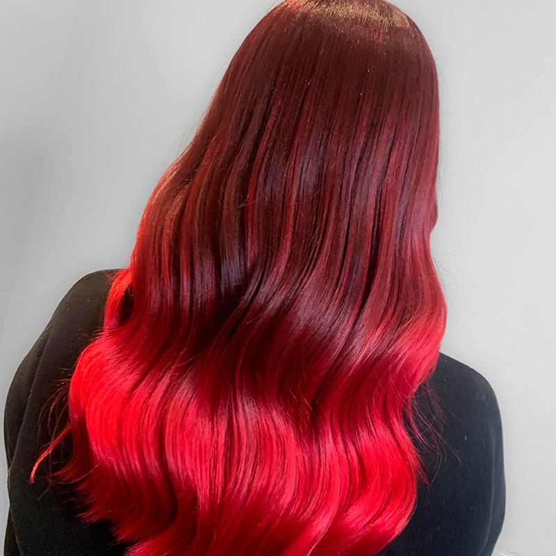 Mujer con cabello rojo con mechas rojas más oscuras, cabello ondulado