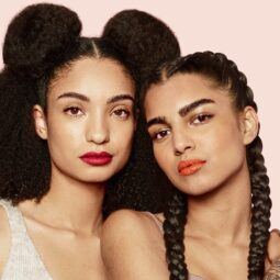 Dos mujeres con distintos tipos de cabello, una Una con cabello afro voluminoso y otra con dos trenzas holandesas