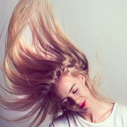 mulher chacoalhando a cabeça com cabelo longo loiro