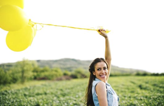 mulher com cabelo liso e longo segurando balões