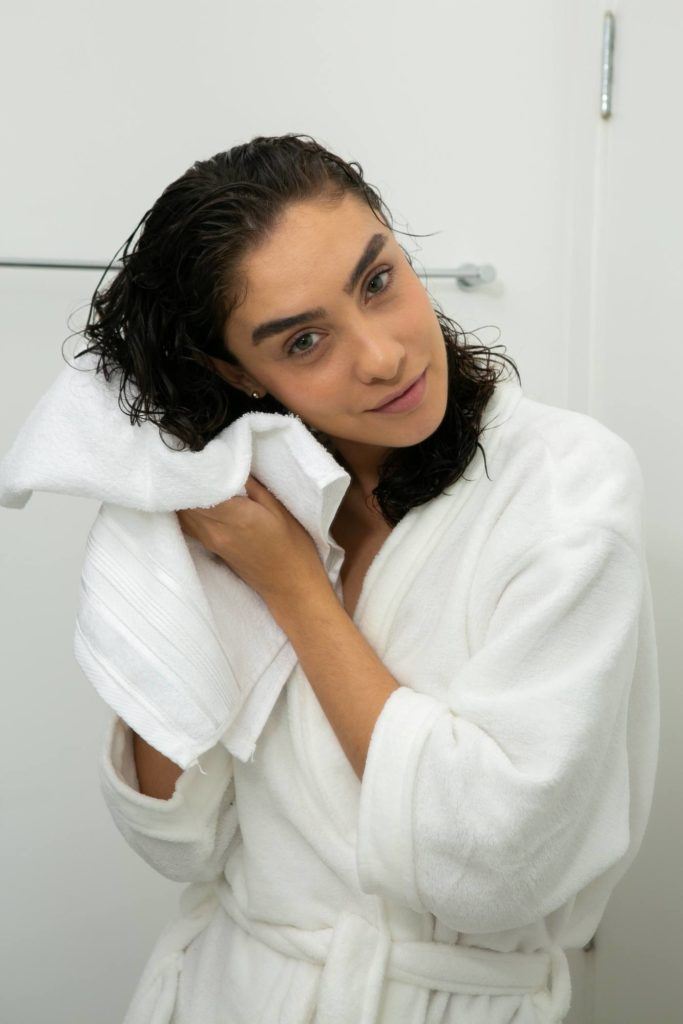 modelo de cabelo cacheado secando os fios com toalha