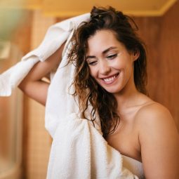 Modelo secando os cabelos molhados com toalha após o banho