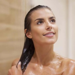 Lavar o cabelo com água mineral: mulher morena tomando banho