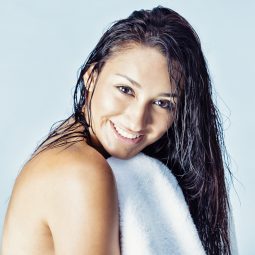 Mulher com cabelos molhados segura toalha de banho