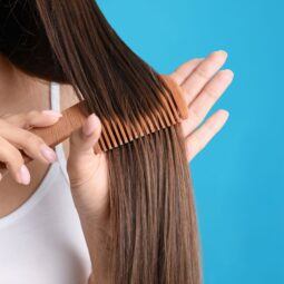 mulher penteando o cabelo com pente de madeira