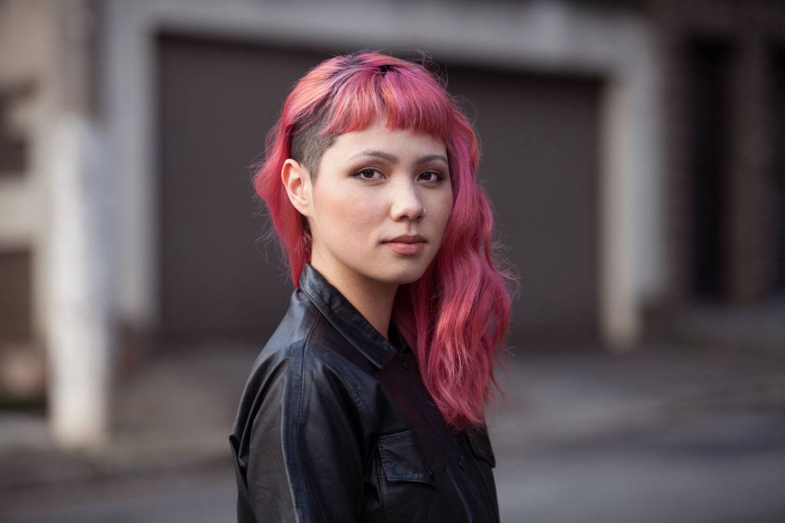 mulher com corte assimétrico e cabelo rosa mostra o estilo das asiáticas.