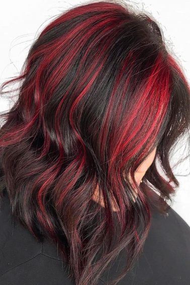 mulher com cabelo desfiado preto pintado com mechas vermelhas olhando para baixo