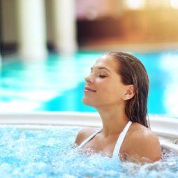 Mulher de biquíni branco na piscina ilustra matéria sobre água termal no cabelo