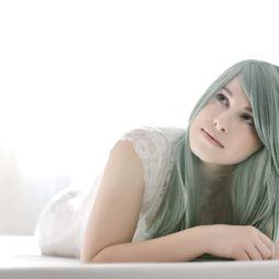 Mulher com cabelo verde água usa blusa branca